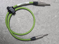 Green and black braided audio cable on a gray surface