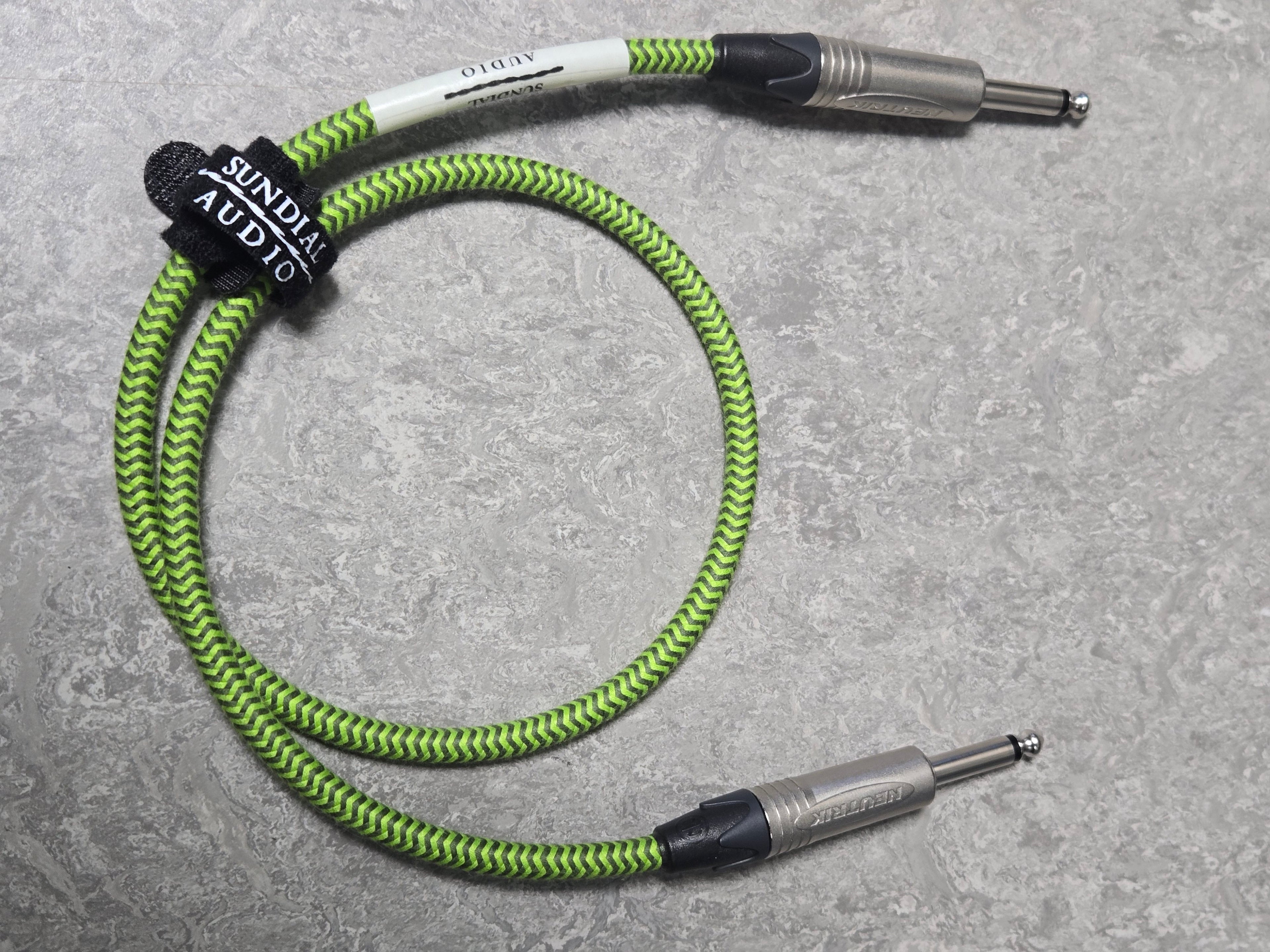 Green and black braided audio cable on a gray surface