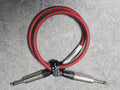 Red and black braided cable with a silver connector on a gray background
