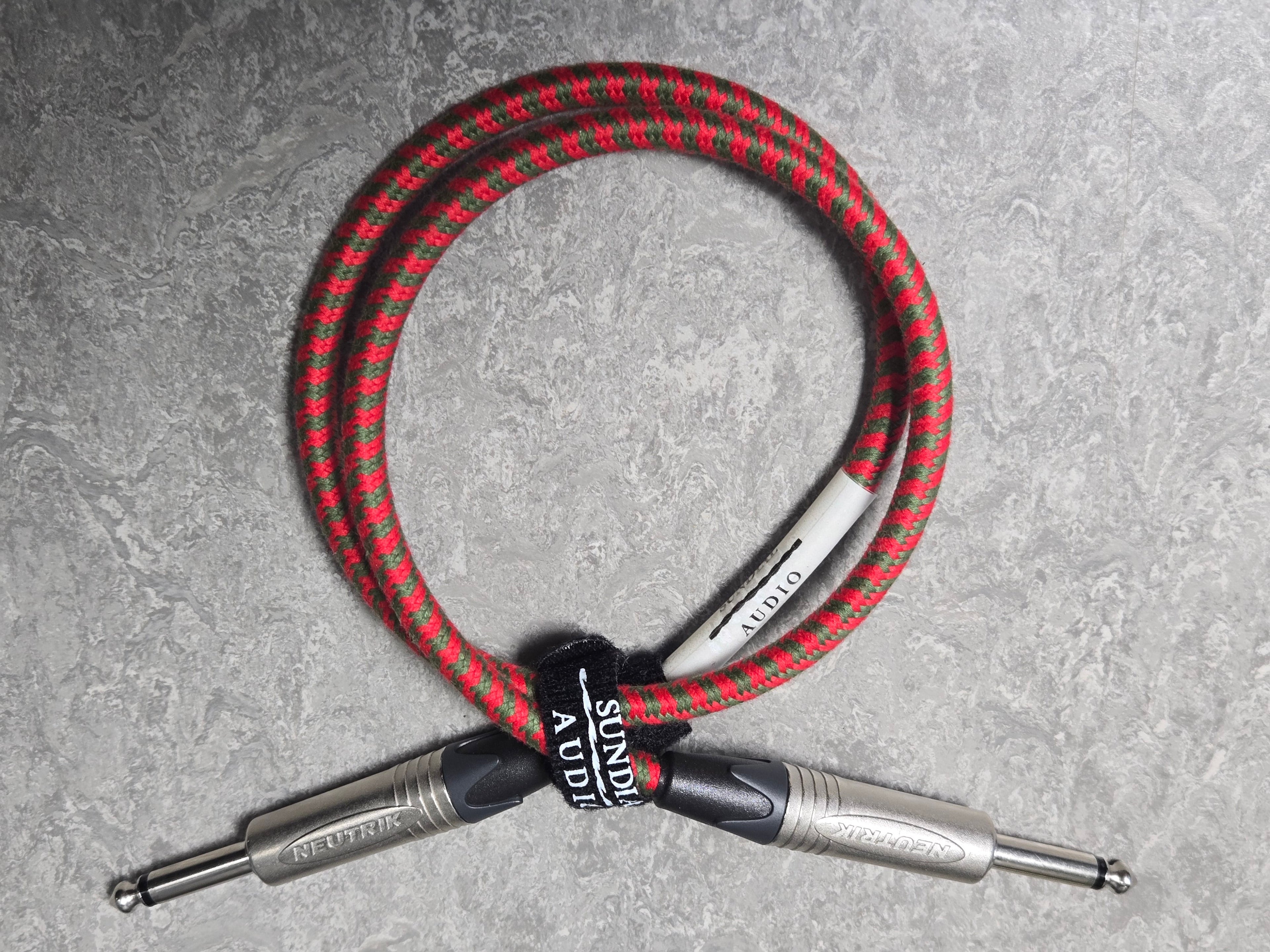 Red and black braided cable with a silver connector on a gray background