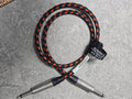 Black and orange braided audio cable with silver connectors on a gray surface