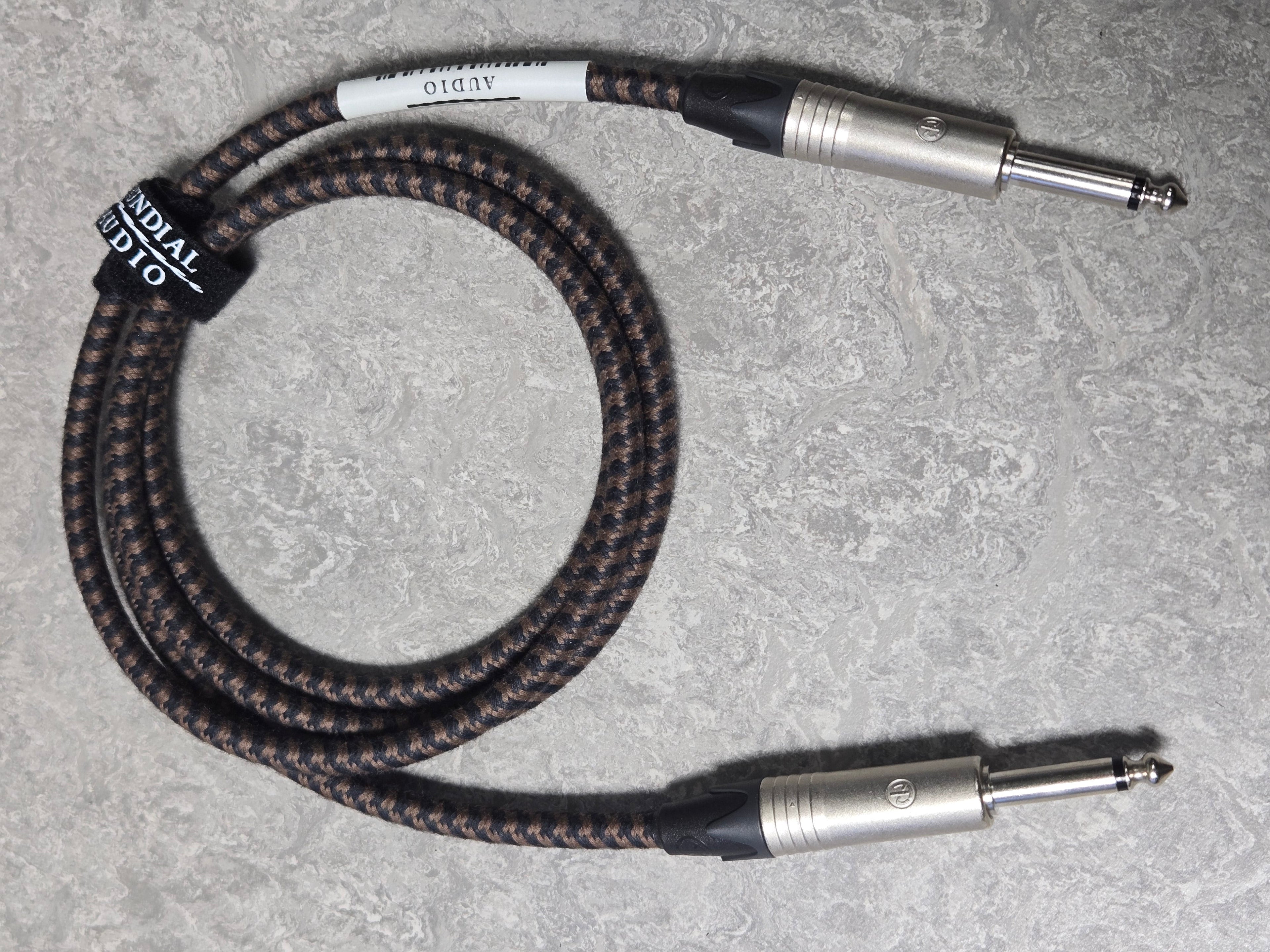 Braided audio cable with metal connectors on a gray surface