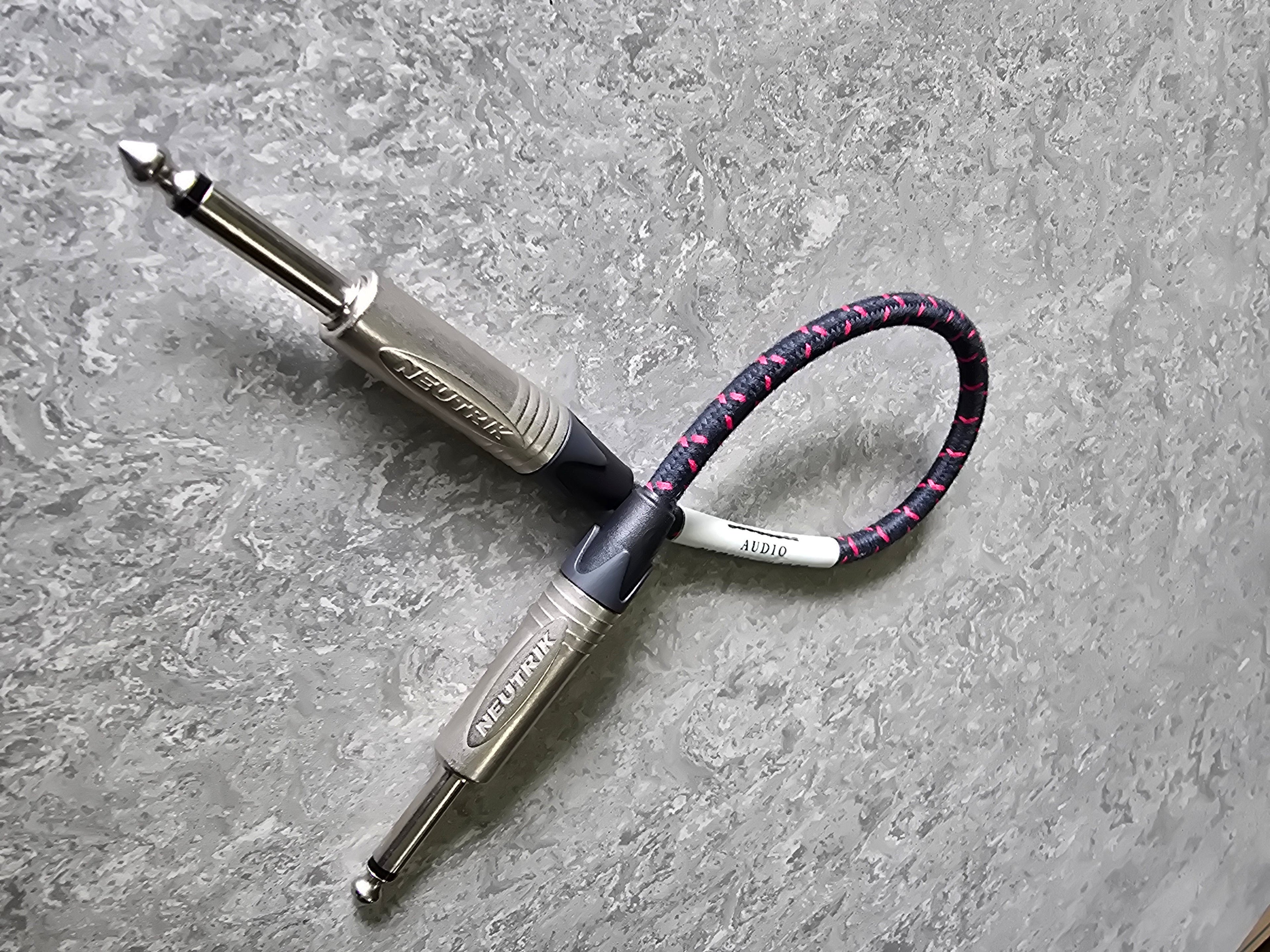 Two guitar effect pedals with a cable on a gray surface